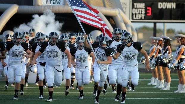 Senior Josh Holland, carrying the flag, leads the team onto Nelson Field. Each week, the team captains vote on a player who has been the hardest worker with the best attitude  to carry the flag. 