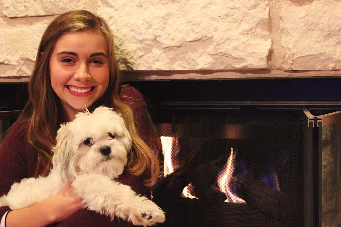 Lauren cozies up with her puppy, Murphy by the fireplace in her home where she will celebrate Thanksgiving with her family.  