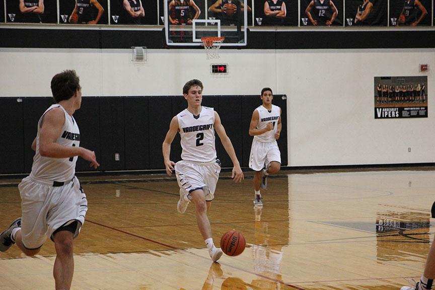 Senior Drayton Whiteside dribbles down the court with Ryan Boles and Alex Fernandes. 