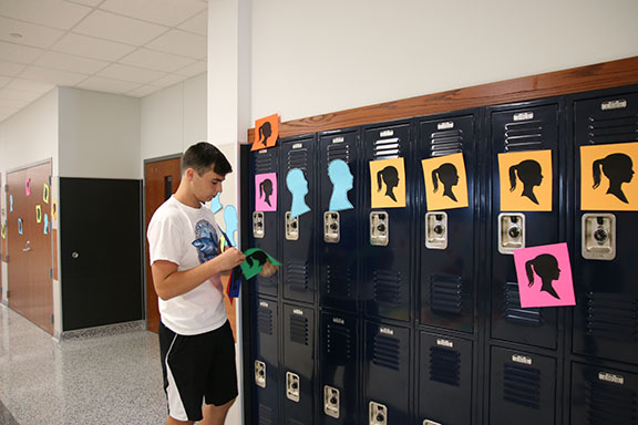 Senior John Richard hangs silhouettes on the walls for Red Ribbon Week to represent people that have died from drug overdose.