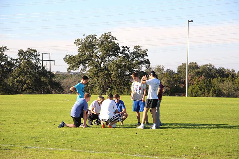 The ultimate frisbee team confers with their coach during practice.