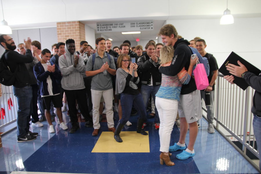 Kirsten Mulligan hugs Nick Hughes after receiving the Change Your School award as the football team cheers. 