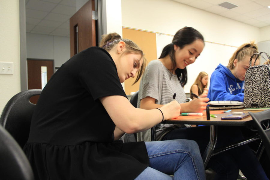 Junior Sydney Sheneman (left) writes down affirmations with friend Alina Vo (right).