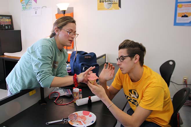 Seniors Bella Castillo and Kevin Hammer shape the top of their ice cream cone, which was made out of mashed potatoes and then colored with food coloring. 