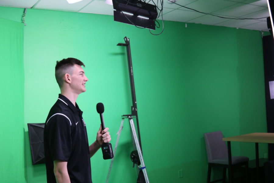 Junior Noah Bailie reads off the teleprompter while recording the broadcast.