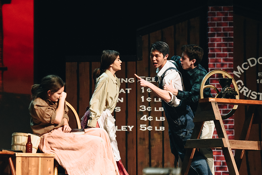 Maggie McDonald, played by alternate Anna Zavelson (9), protects Belinda McDonald, played by alternate Sixtine Ronchi (12), as her father, Black McDonald, played by Francis Kim (12), goes after her in a moment of rage. Dr. Jack, played by Carlos Alvarez-Roth (12) attempts to keep him off.