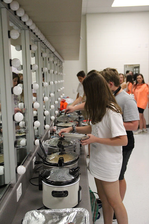 Students line up in the dressing room to get dinner. Almost every student brough crock pots filled with food so the entire cast and crew could eat a full meal during rehearsal. Schneider named the rehearsal the “crock pot rehearsal” for that reason. 