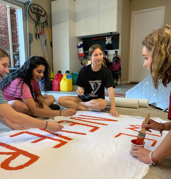 FCCLA officers Megan Henry, Harshita Avirneni, Elise Cuellar and Anatalia Felicita Beiler joke around while painting a banner for their float.