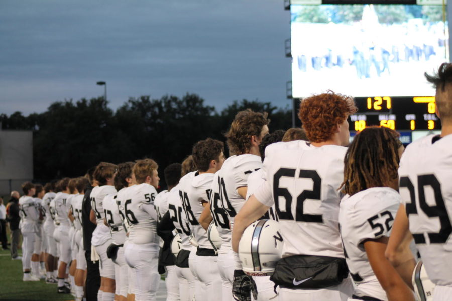 The varsity football team lines up for the national anthem against Mcneil.