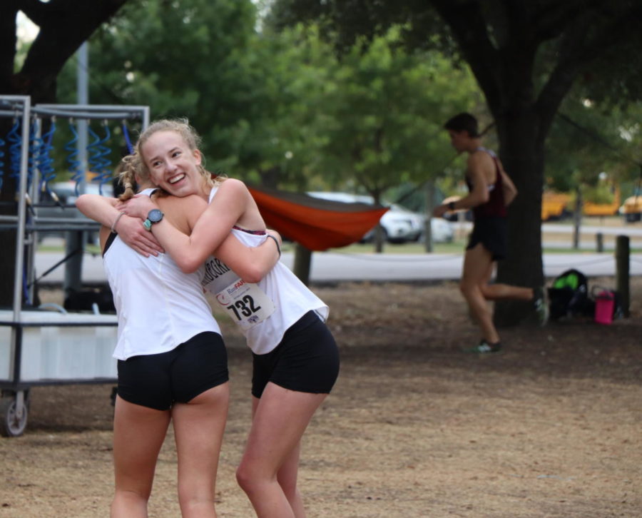 Junior varsity runner Sophia Peterson hugs her teammate after her win.