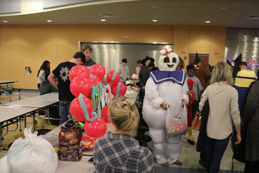 Freshman Karina Brown hands out candy to children surrounding the "Ghostbusters" themed robotics trunk.