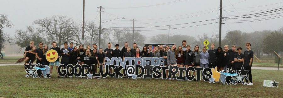 The+swim+team+posing+in+front+of+their+good+luck+sign+after+districts.+