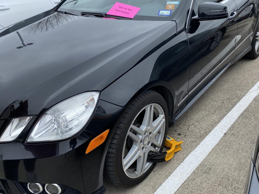 Unidentified car without parking pass gets booted in front lot.