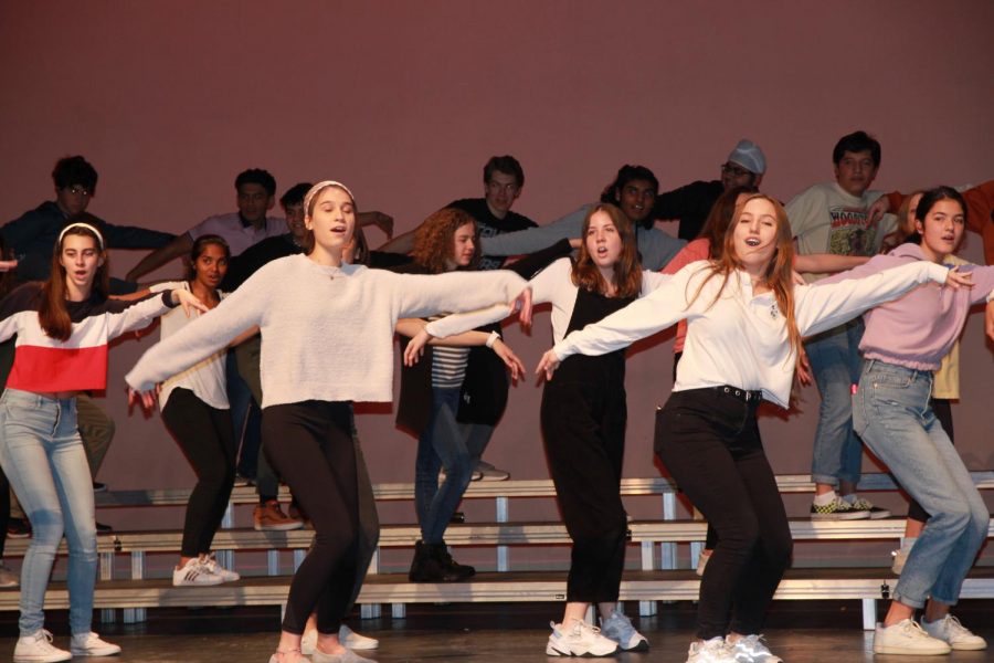 Choir rehearses performance with choreography to the song Love Shack by the B-52s 