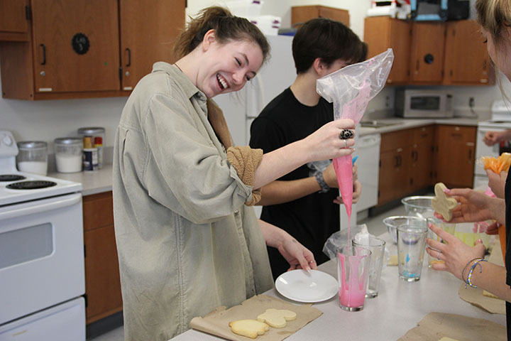 Sophomore Georgia Balfour begins her process of frosting her butterfly shaped cookie. Balfour used the cookie dipping method to accomplish a tie dye glaze finish. 