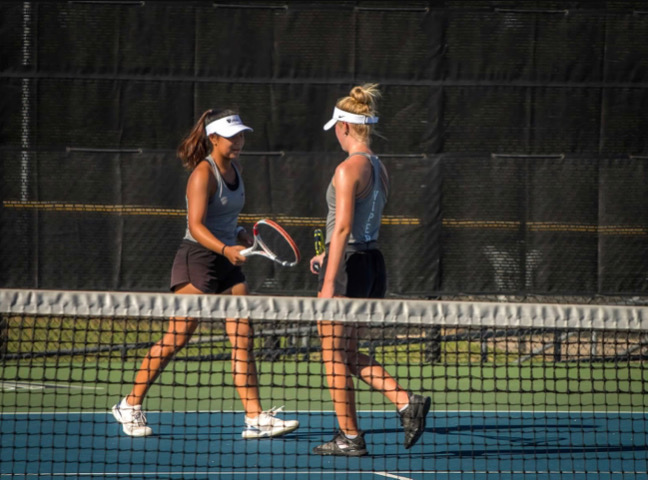 Hitting her racket against her partner freshman Lauren Tin's, sophomore Brooke Childress celebrates a point.