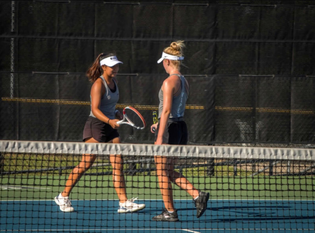 Hitting her racket against her partner freshman Lauren Tins, sophomore Brooke Childress celebrates a point.