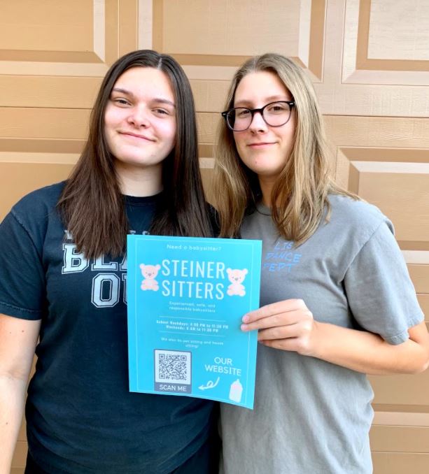 Founder Kira Anderson and Co-founder Shelby Thickstun holding a flyer for their recently launched buisness: Steiner Sitters