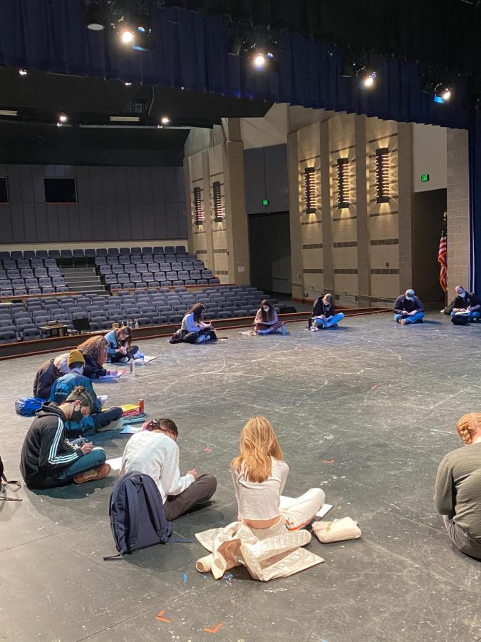 Masked OAP actors gather and rehearse in the schools auditorium.