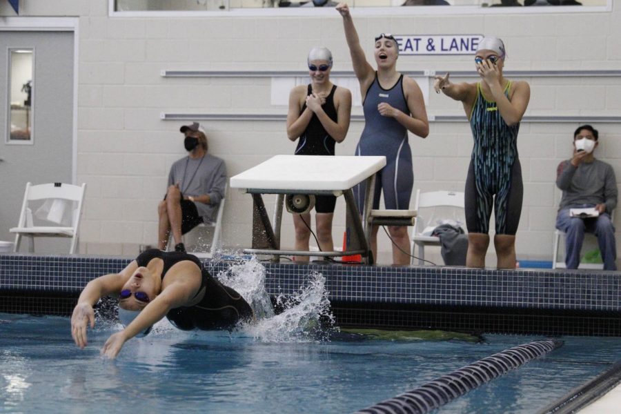 Junior Avery Wong dives back as teammates cheer her on.