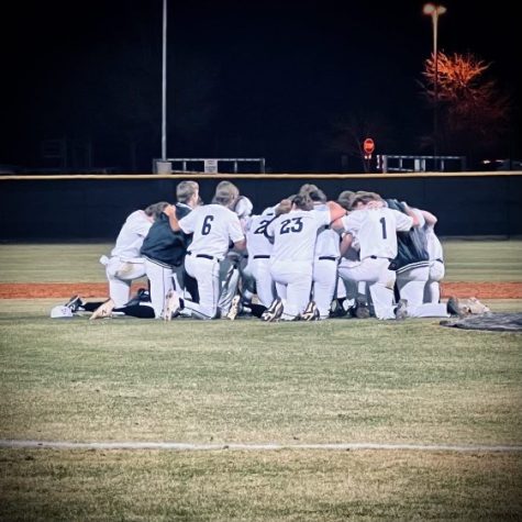 Varsity boys baseball huddle together after beating their opponents.