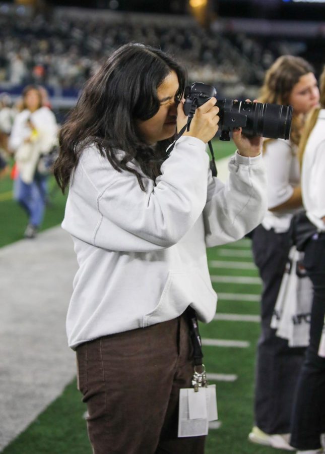 Wearing her press pass and photography tip card, junior yearbook editor Kylie Pucong takes pictures of the final play of the game.