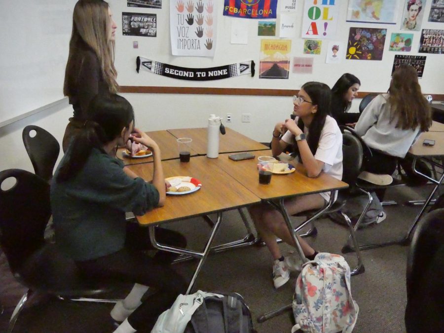 Students eat and talk with their friends, enjoying the potluck.