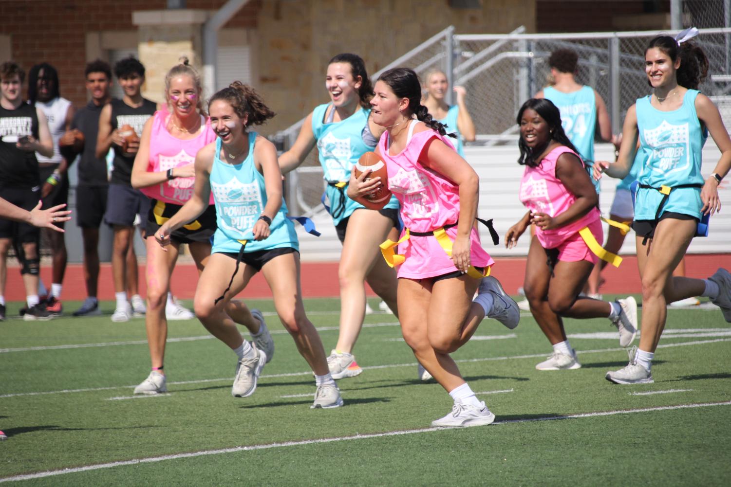 Players run for the ball. Powder Puff is played at schools across North America. 