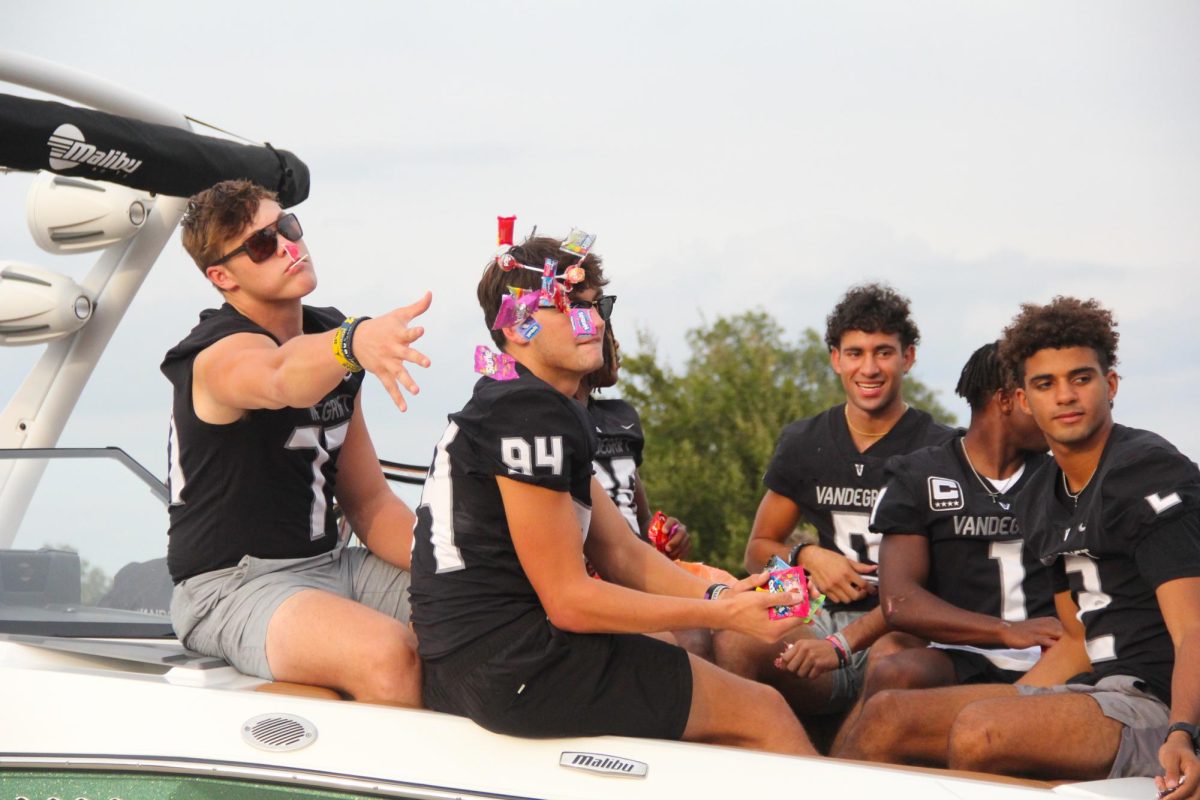 On Wednesday during the Homecoming parade, senior Blake Frazier tosses candy from the front of the varsity football teams float boat. Many teams and clubs used boats as their platforms.