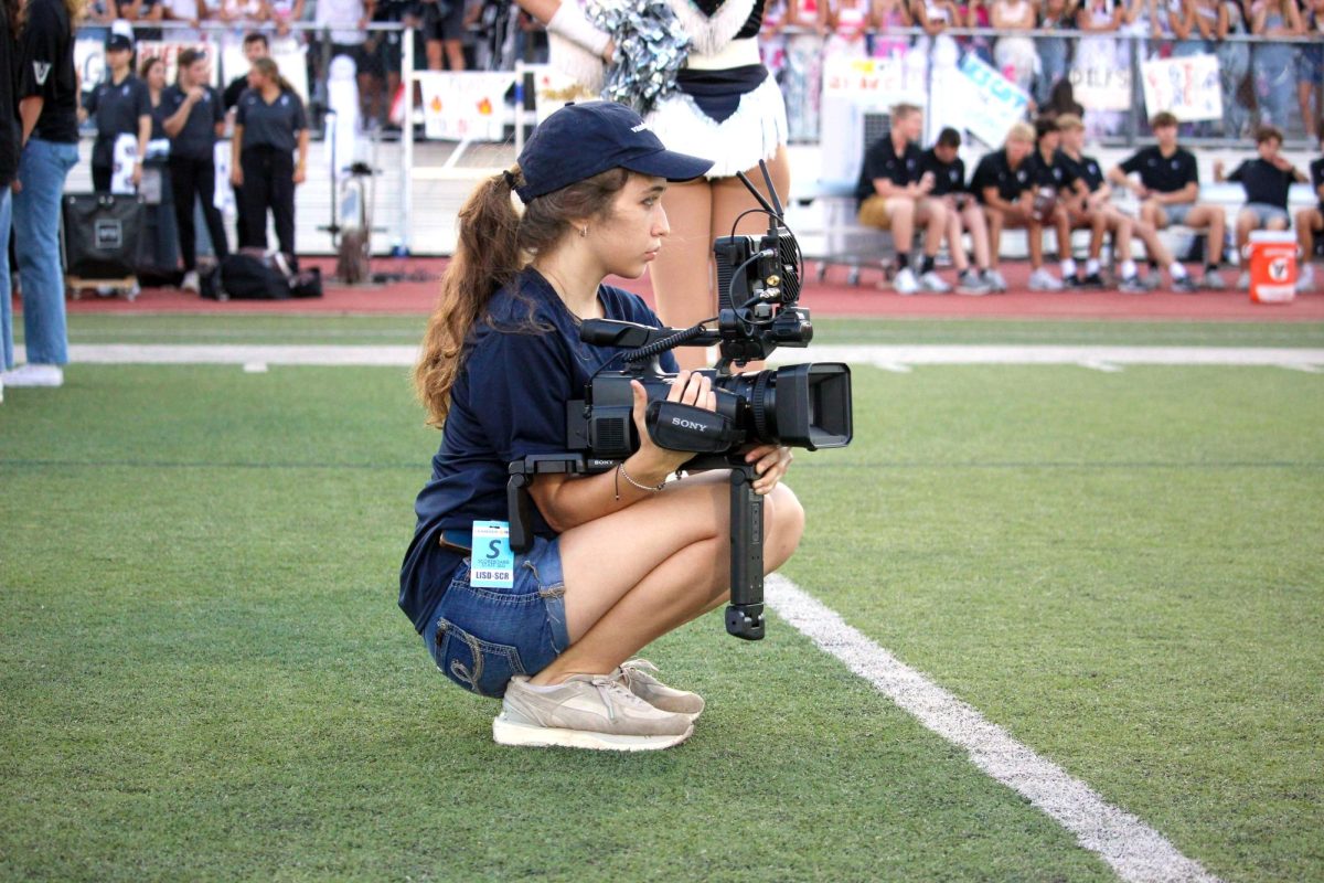 During the Homecoming game, junior Ava Vanna takes video. Vanna founded the film club.