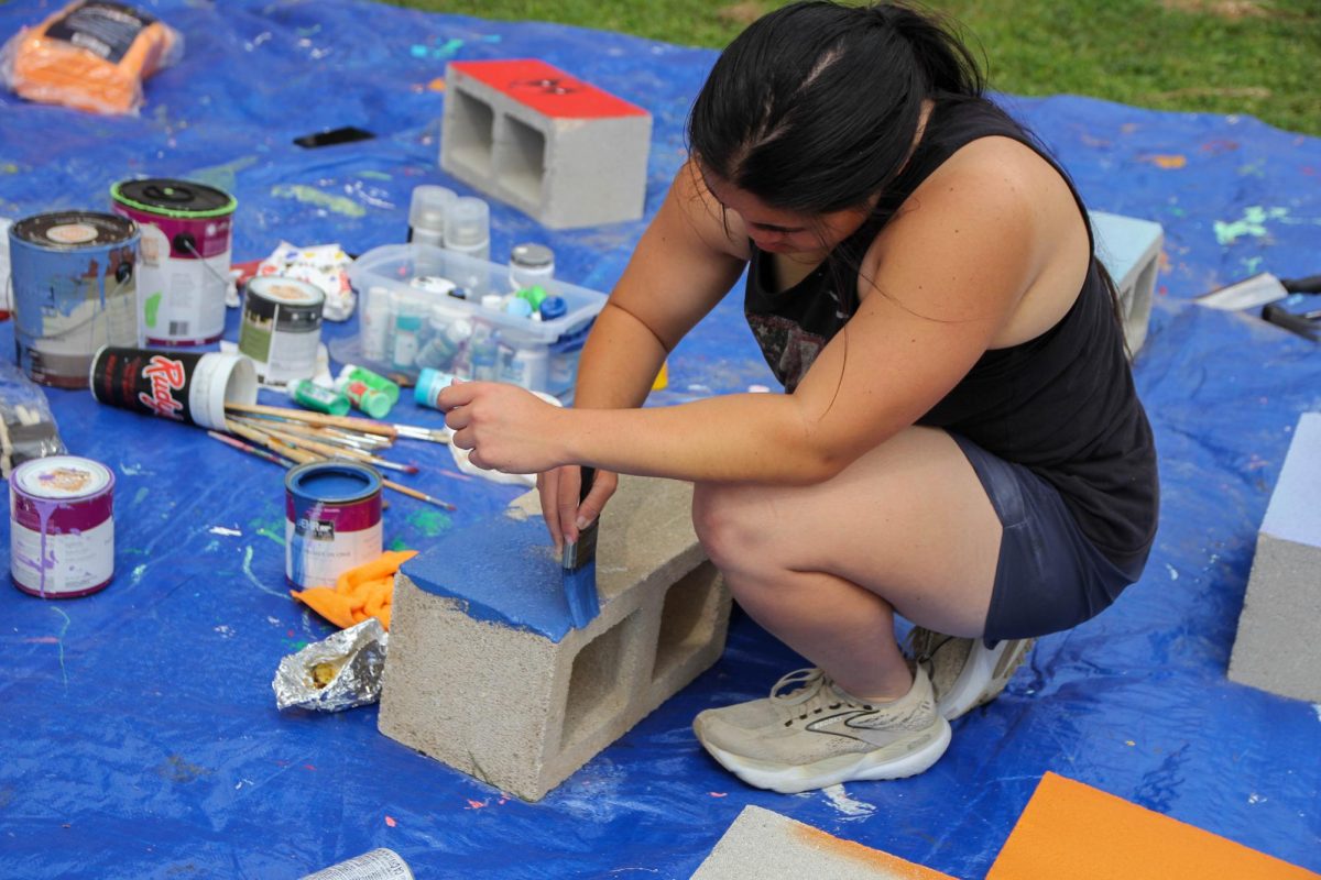 Senior Seraphina Chu paints a cinder block to add to the planters. 