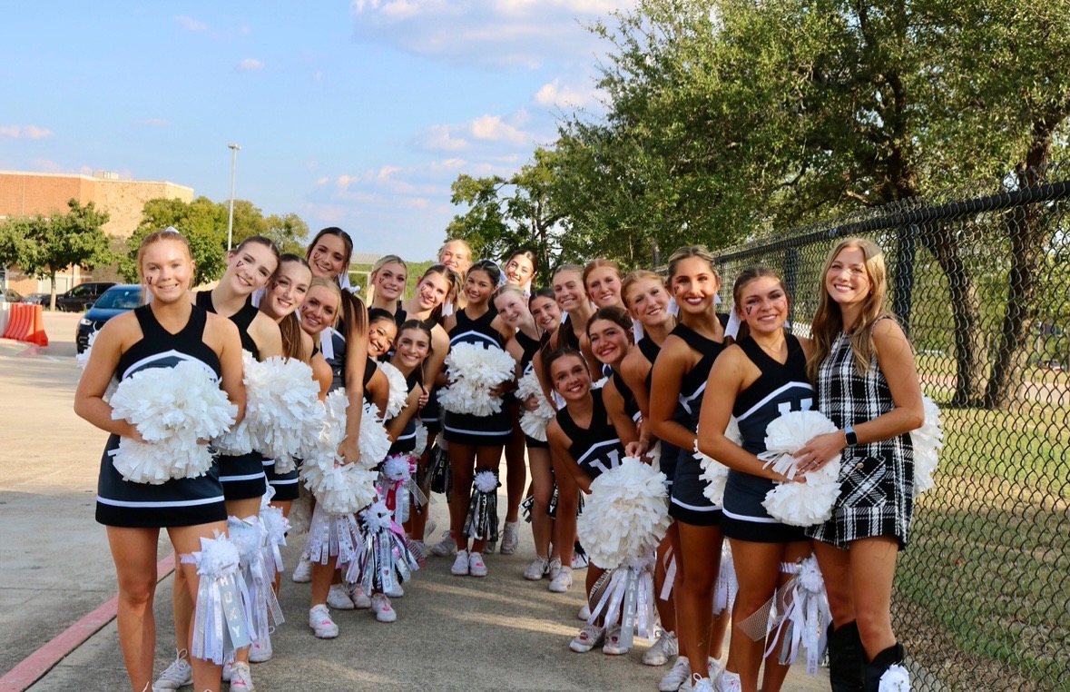 Head Coach Sydney Warlock and the varsity team poses for a photo before the Homecoming game. Each member of the team had a mum, with seniors going all-white. "Something I would love to happen this year is for the girls to get top five at both competitions," Warlock said.
