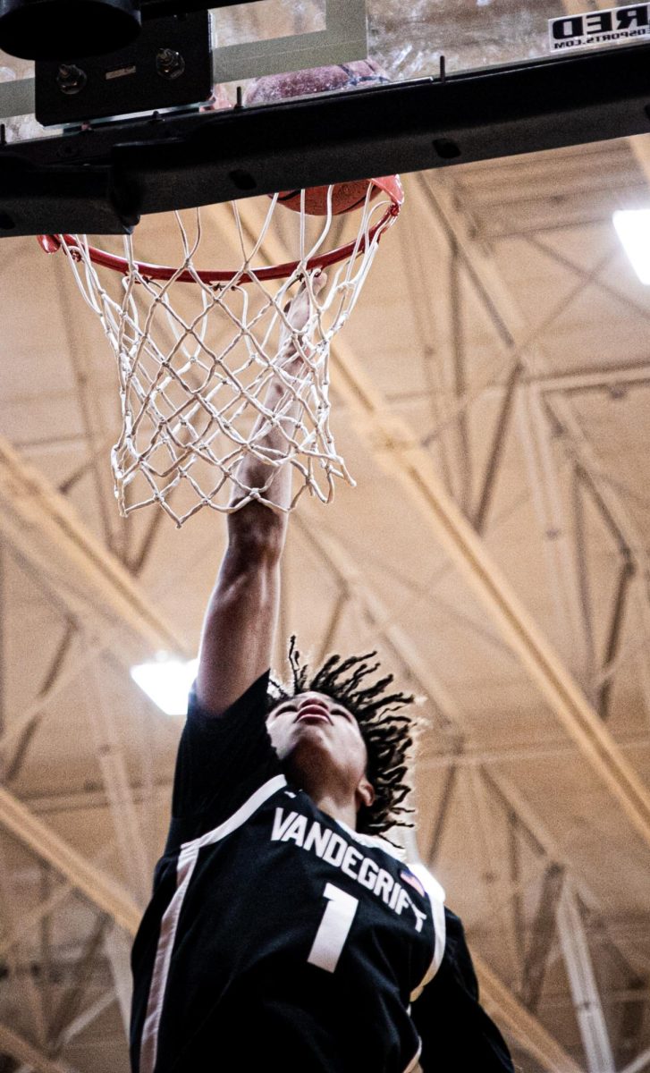 Junior Destin Herring goes up for a dunk while warming up for the second half of the game. 