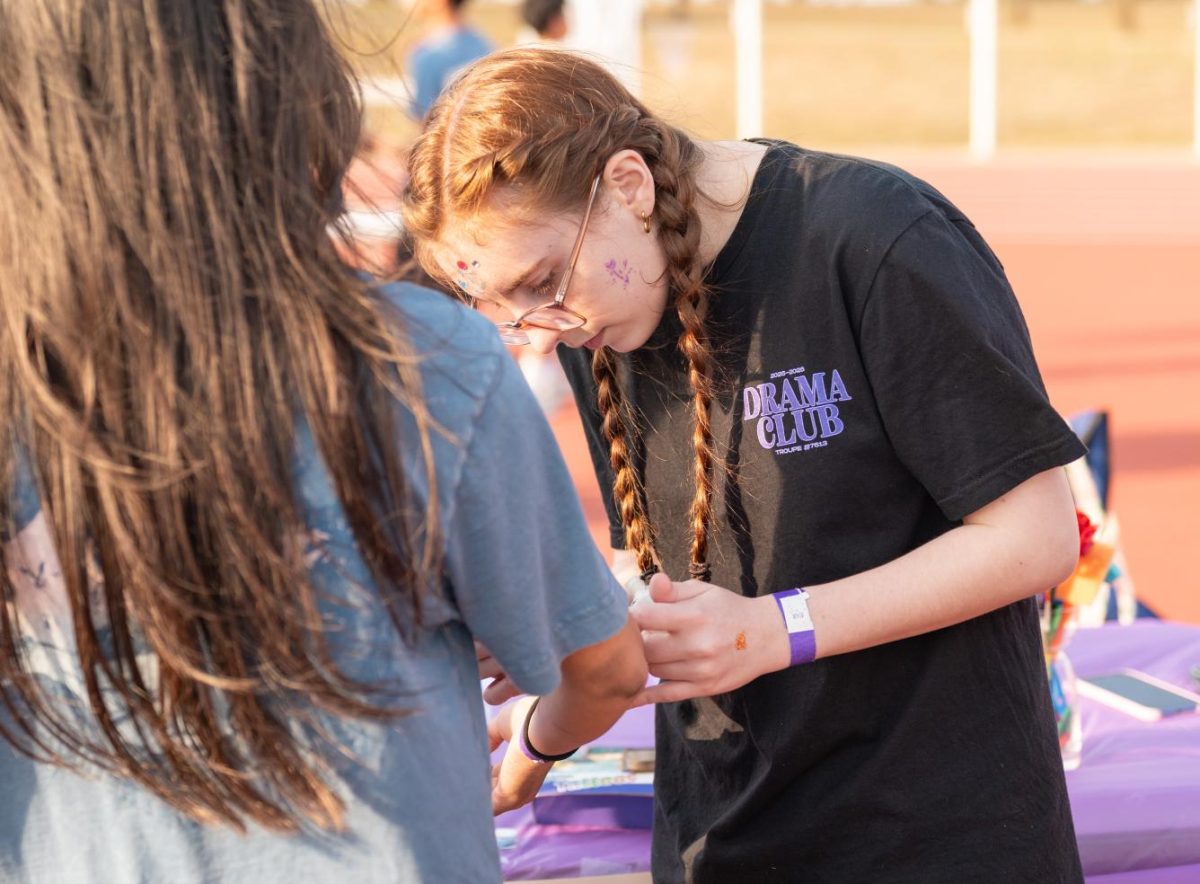 Sophomore Megan Gary applies glitter tattoos at the Drama Club booth. On Friday, March 27, the Drama Club was one of many booths signed up for the team competition.
